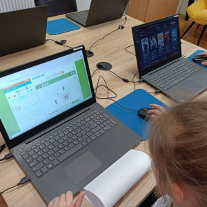 Dziecko rozwiązuje zadania na laptopie.